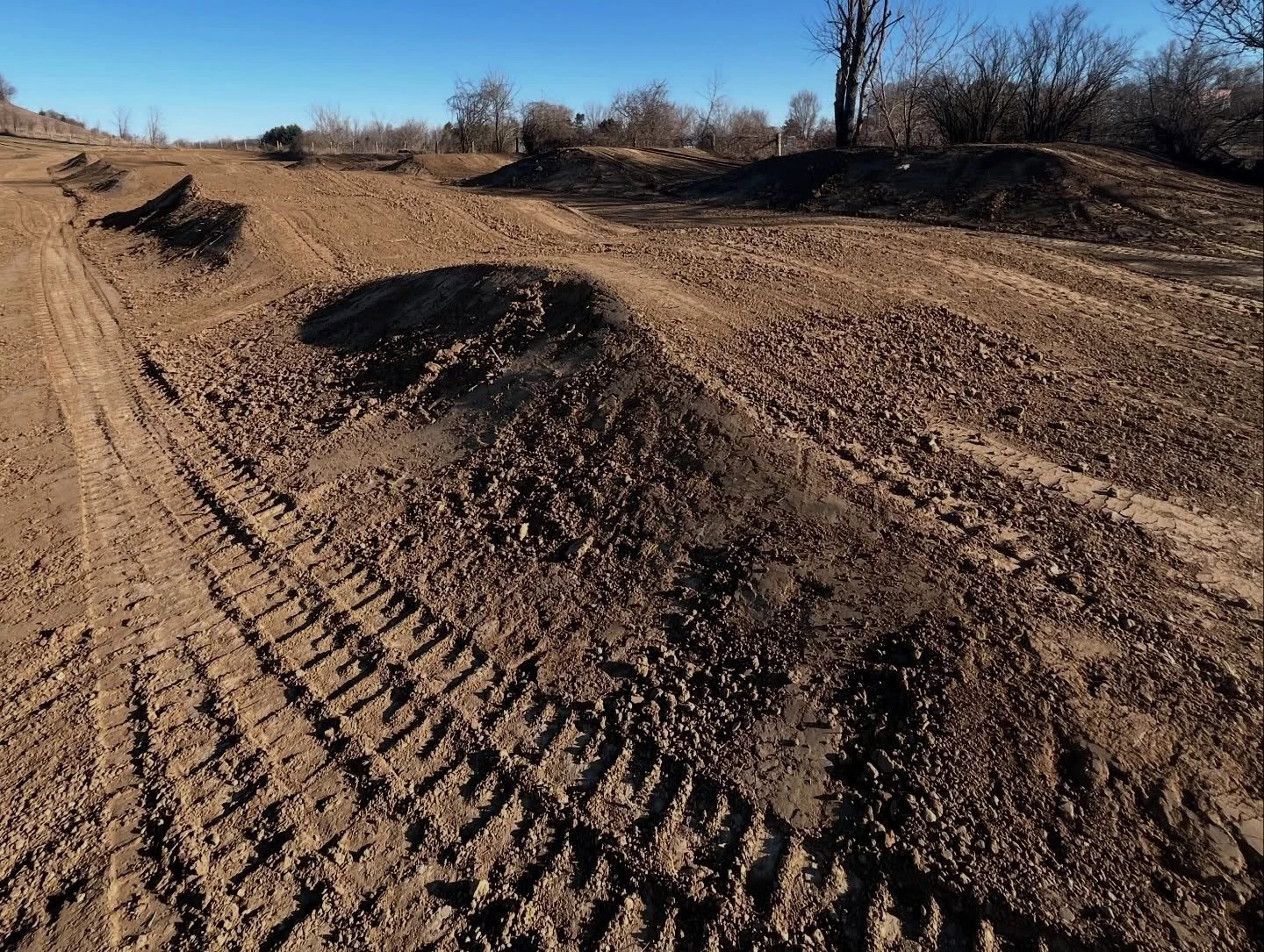 Dirt motocross track with jumps and tire tracks.