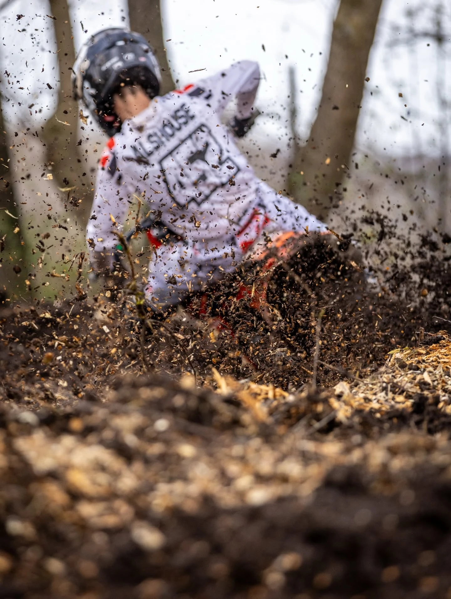 Motocross rider on dirt bike kicking up soil and debris.
